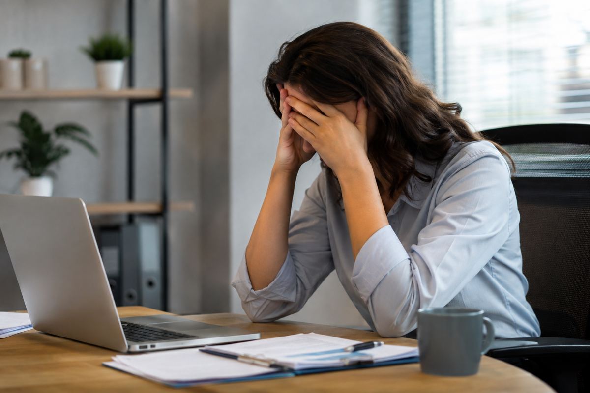 A worker with her head in her hands at a desk